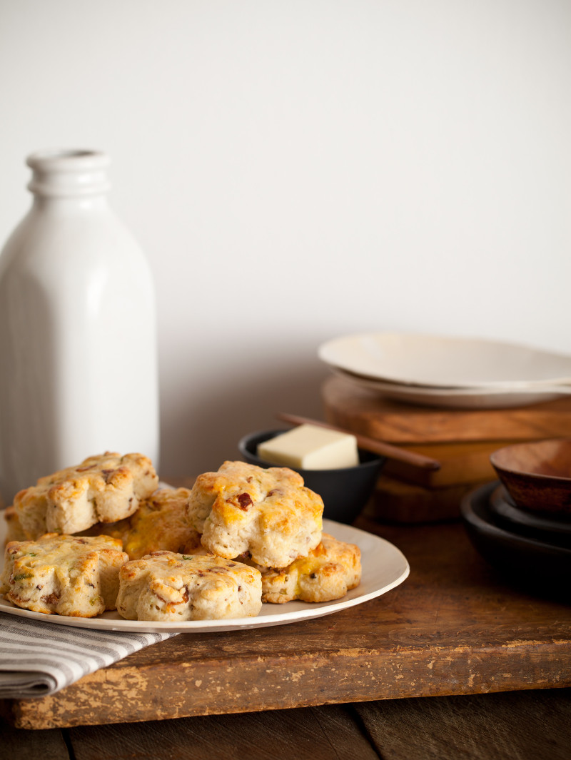 A close up of bacon gruyere and green onion scones next to butter and buttermilk.