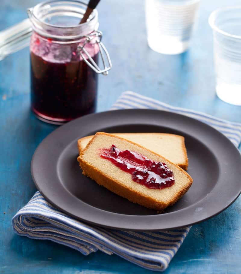 Simple Blackberry Jam An open glass jar of simple blackberry jam and plate of bread with jam.