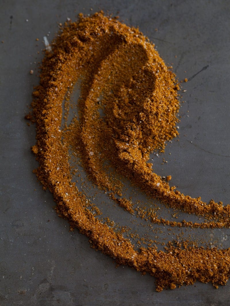 A close up of curry powder artfully placed on a dark surface.
