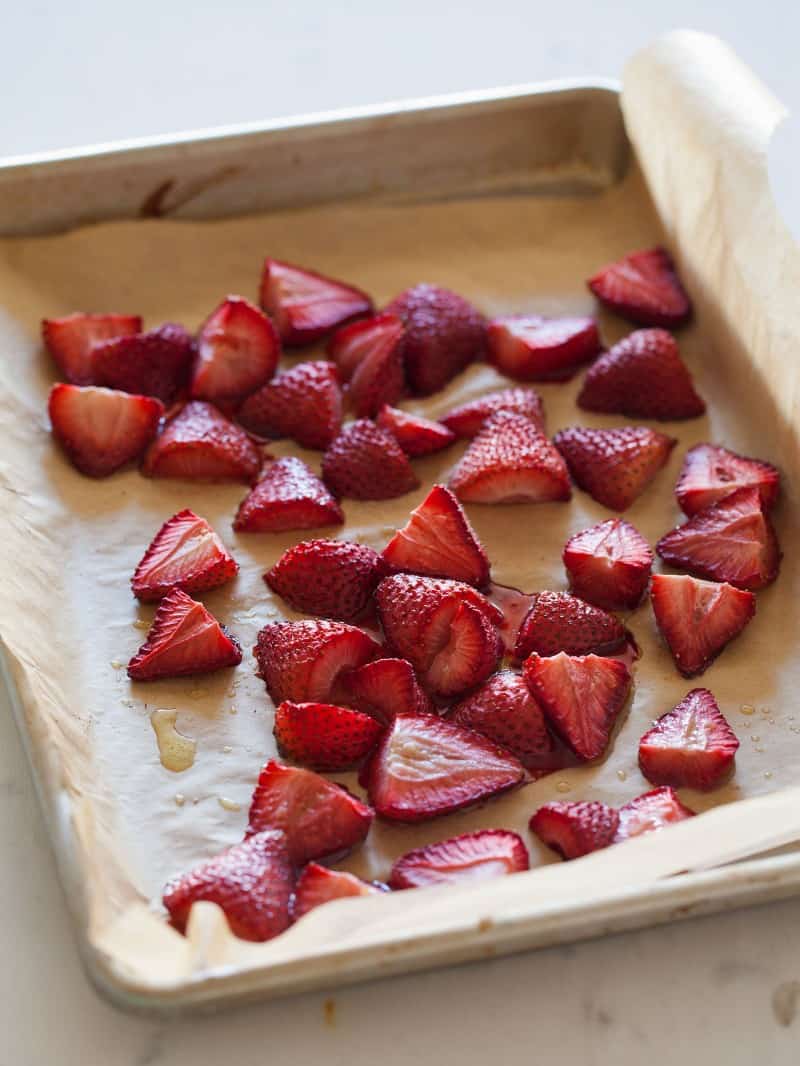 A sheet pan covered in roasted strawberry halves.