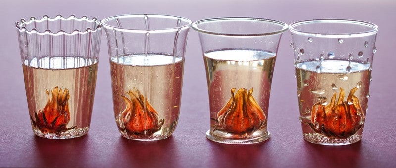 A close up of two hibiscus ginger champagne cocktails with hibiscus flowers.