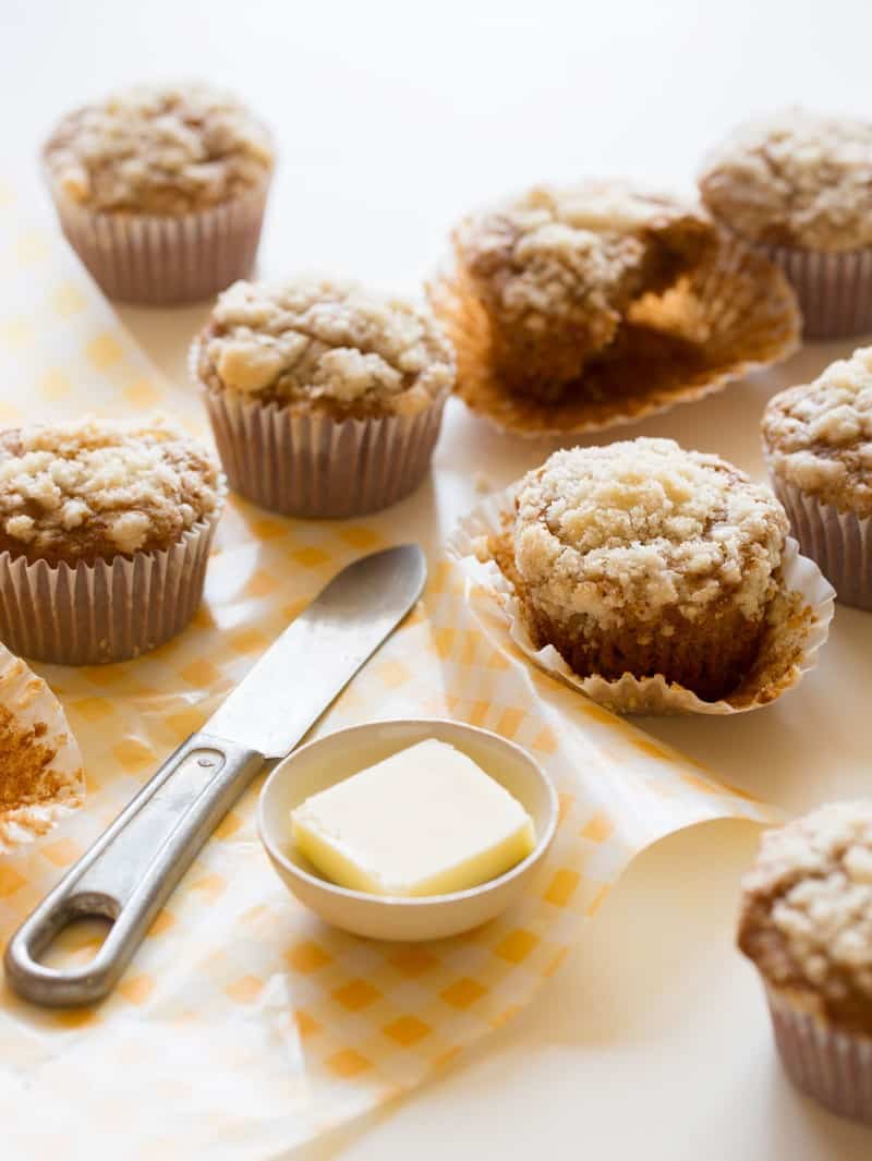 Several streuseled acorn squash muffins next to a ramekin of butter and a knife.