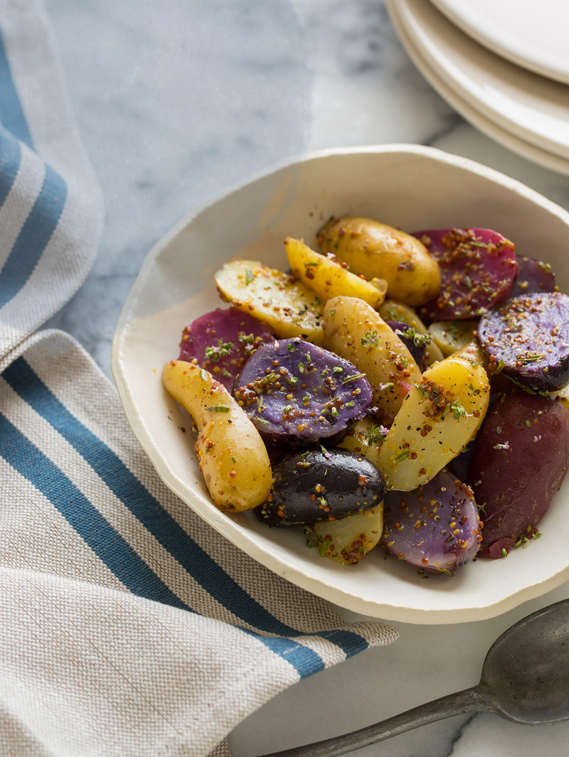 A bowl of warm German potato salad with a blue striped napkin.