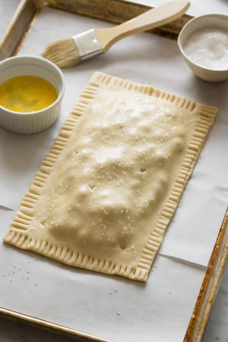 Blueberry Slab Pie recipe A raw blueberry slab pie with a ramekin of beaten egg.