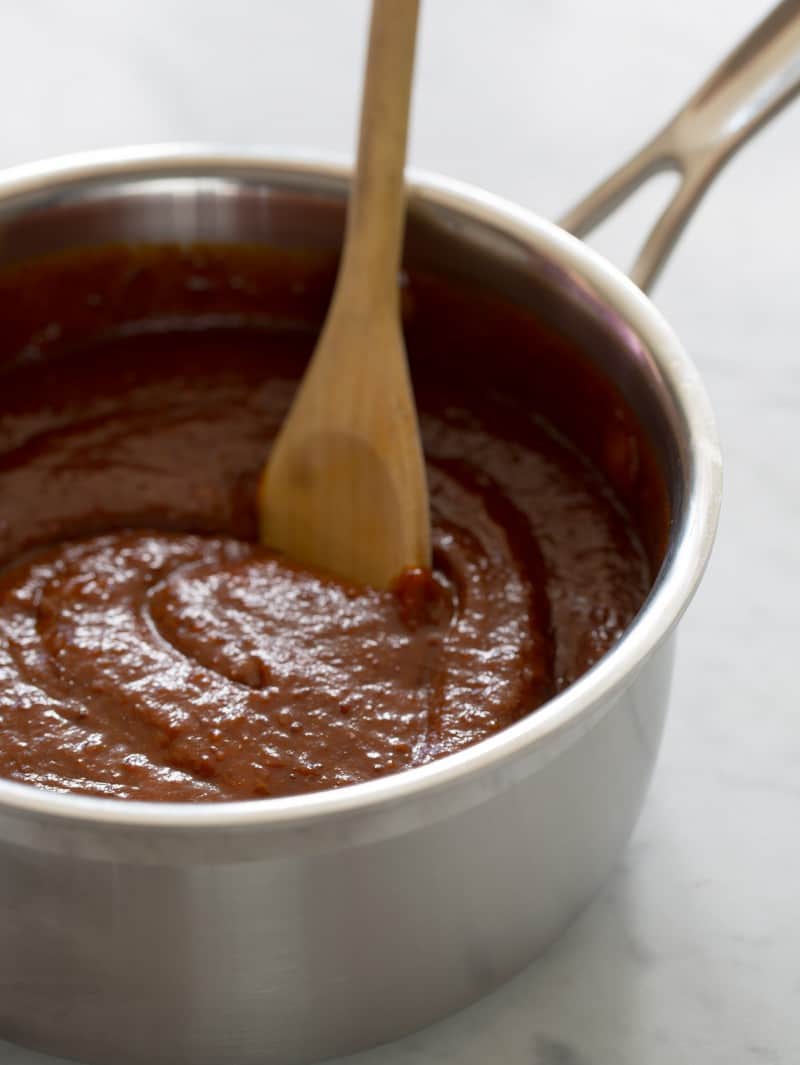 Homemade BBQ Sauce A pot of sweet and tangy BBQ sauce being stirred by a wooden spoon.