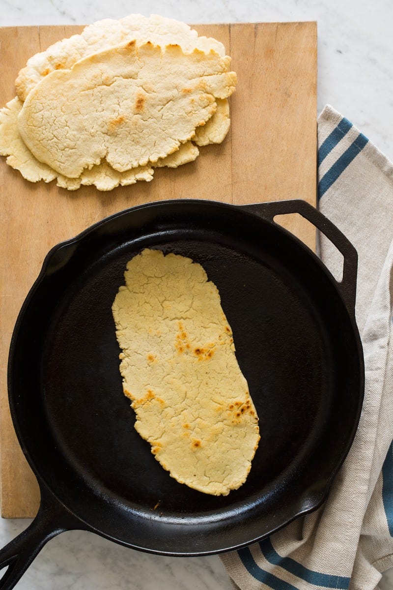 Huaraches in a skillet and finished on a wooden cutting board.