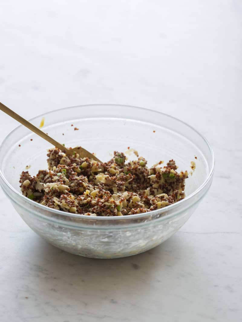 A bowl of mixed ingredients for big veg quinoa burgers with a fork.