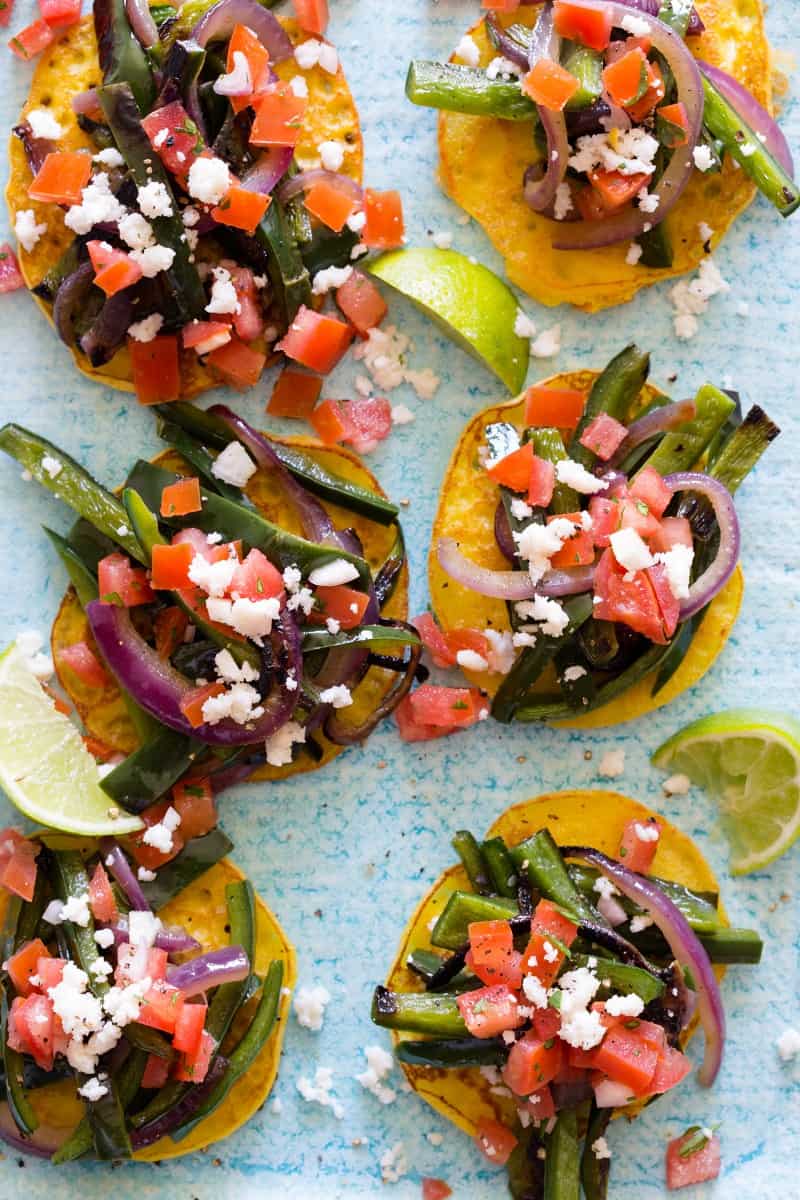 Cachapas topped with veggies and lime wedges.