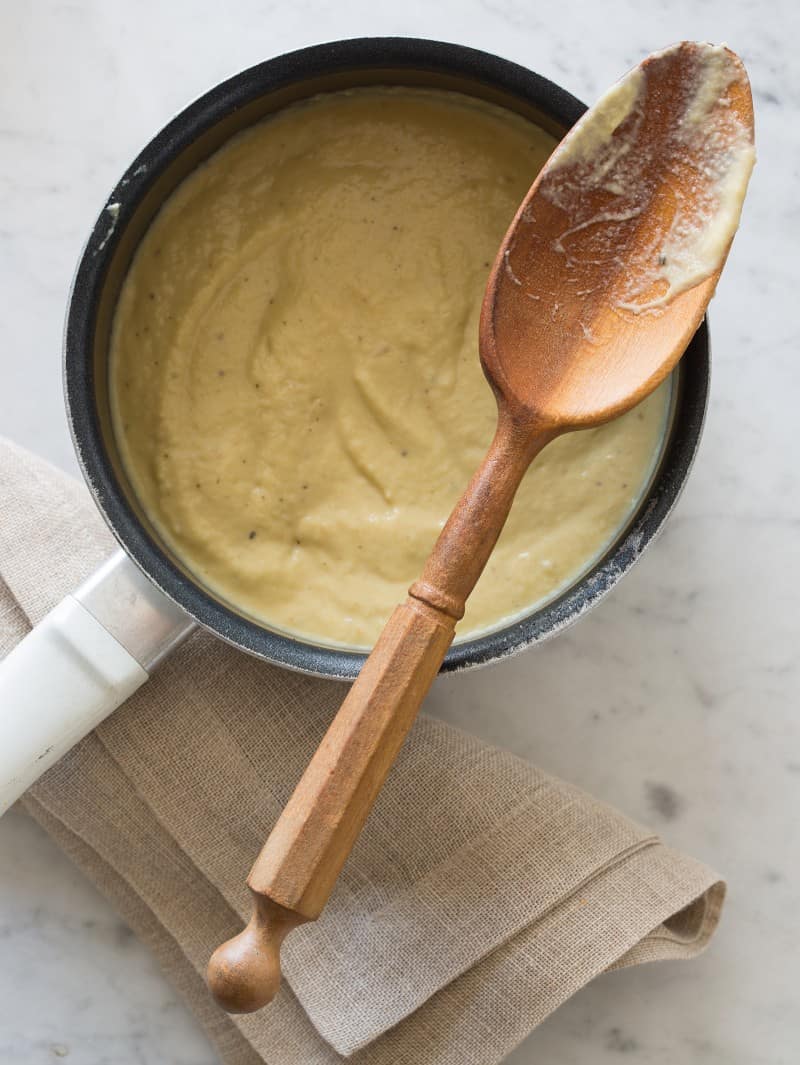 A pan of vegan cauliflower cream sauce with a wooden spoon.