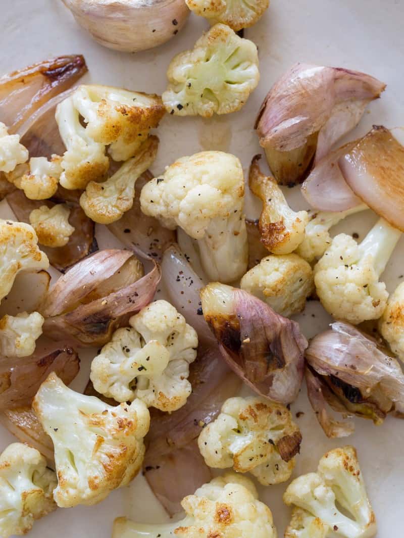 A close up of roasted cauliflower, garlic, and shallots.