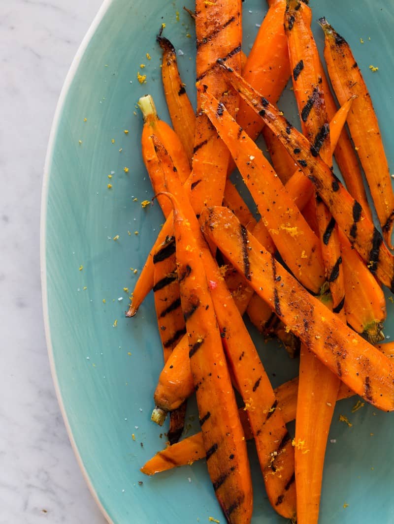 A close up of balsamic grilled carrots on a blue green plate.