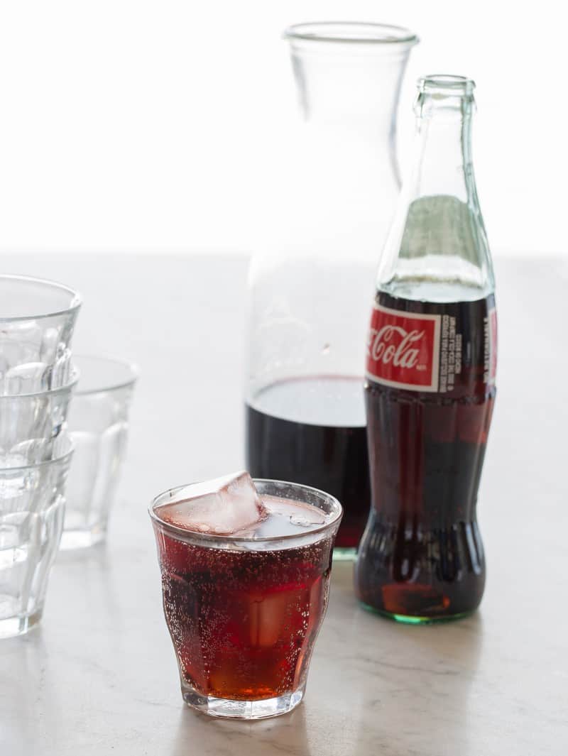 A bottle of wine, a bottle of Coca Cola, and a kalimoxto with extra glasses.
