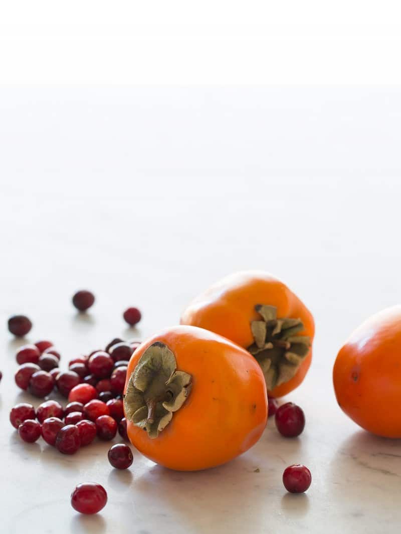 A close up of fresh cranberries and persimmons for spiced chutney.