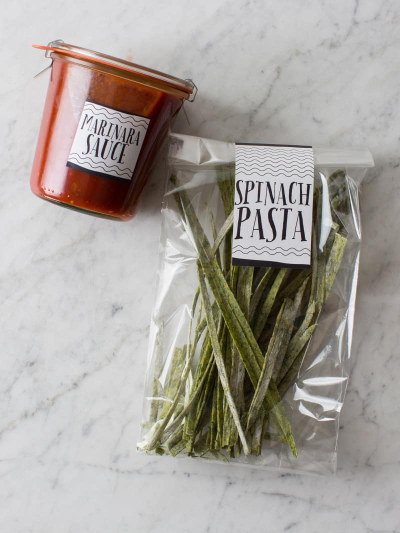 Clear labeled bag of homemade pasta with a labeled jar of sauce.