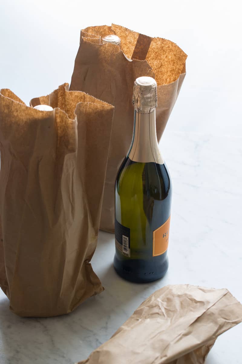 Wine bottles in and next to brown paper bags.