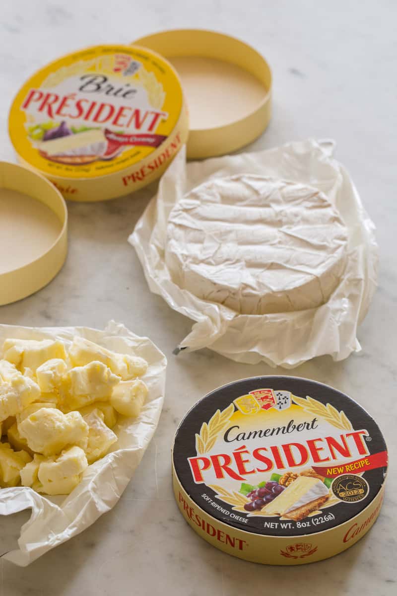 Boxes and open containers of different cheeses for creamy skillet mac and cheese.