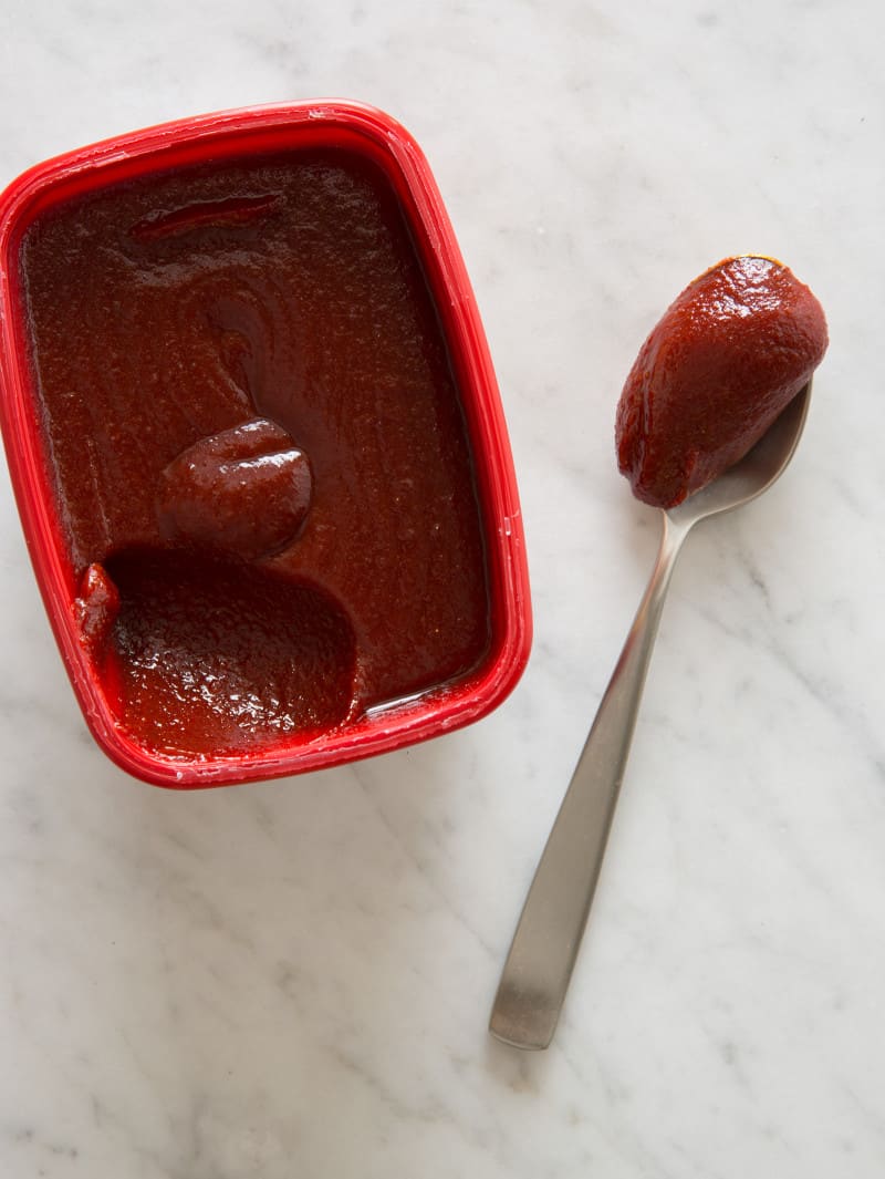 A close up of a container and spoonful of gochujang.