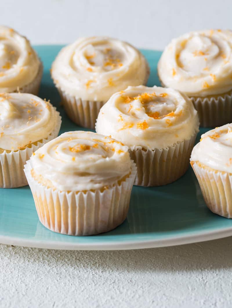 A close up of a platter of butter cupcakes with grapefruit buttercream.