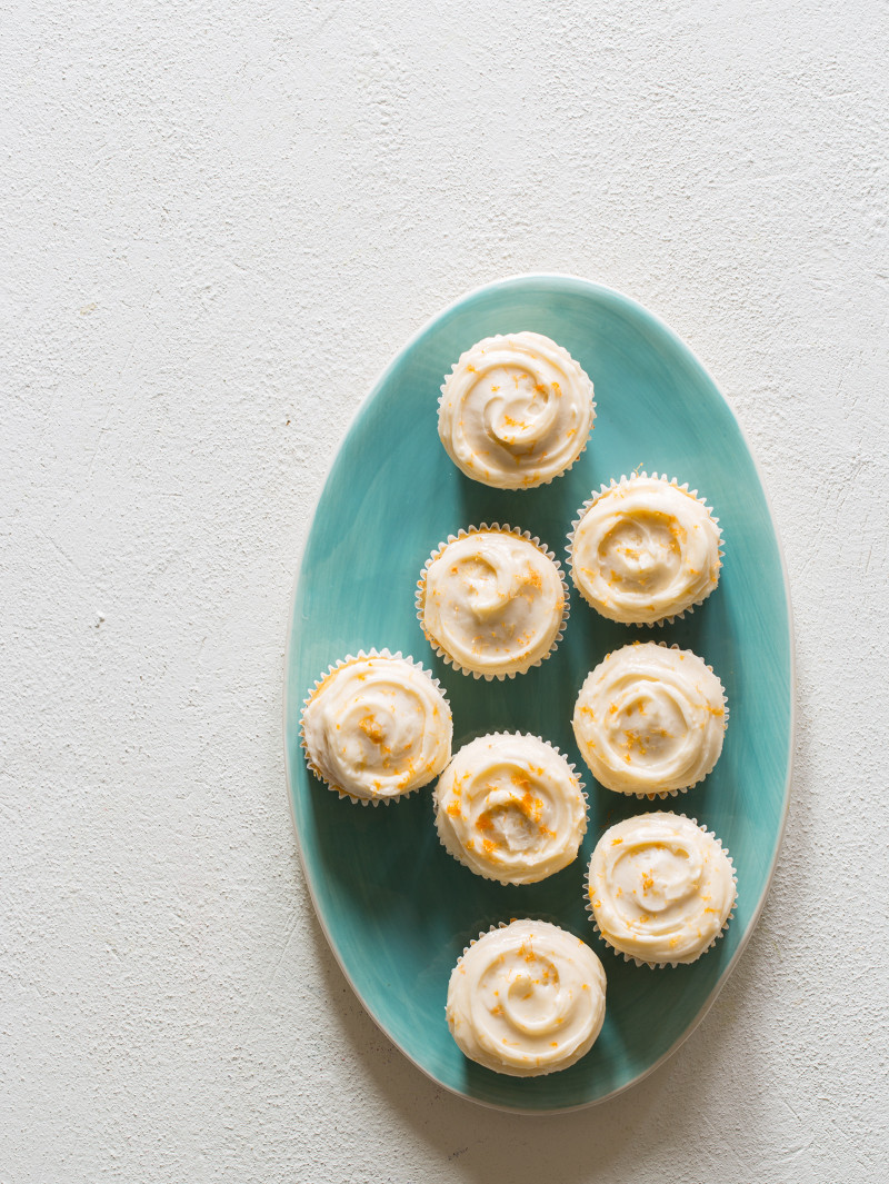 A green platter of butter cupcakes with grapefruit buttercream.