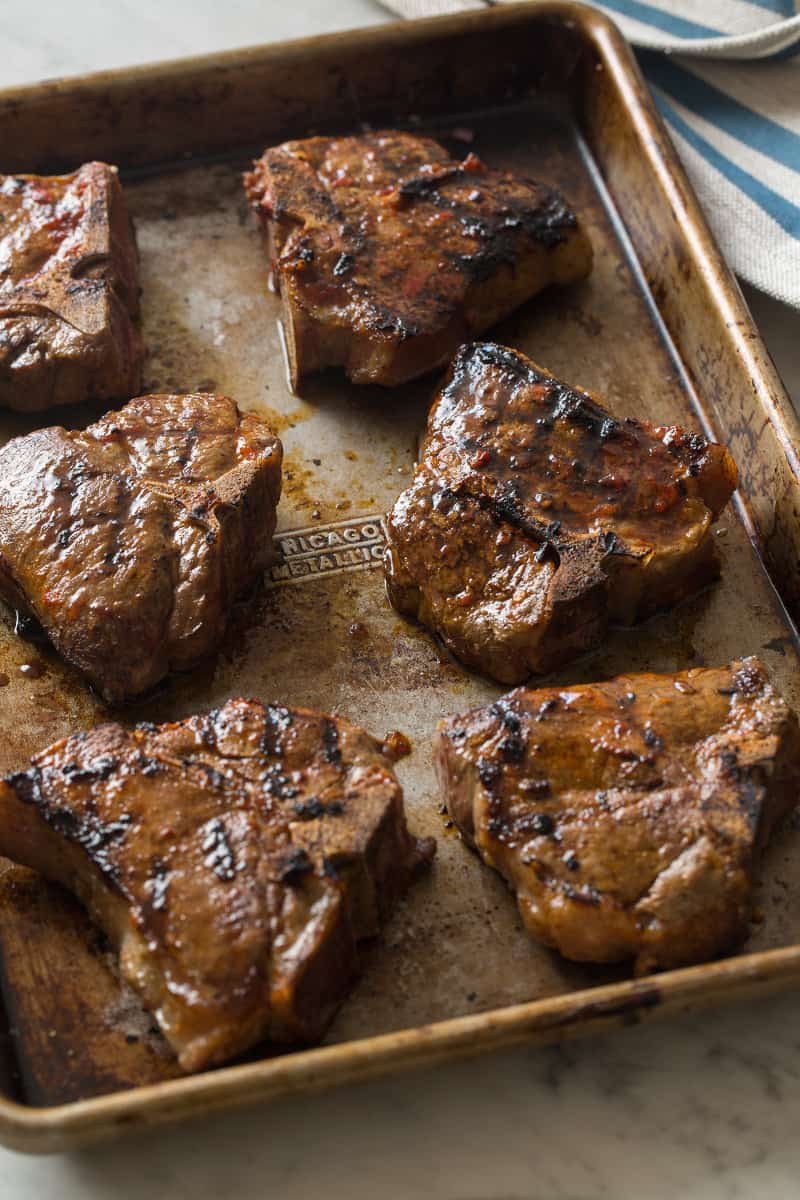 A close up of harissa grilled lamb chops on a sheet pan.