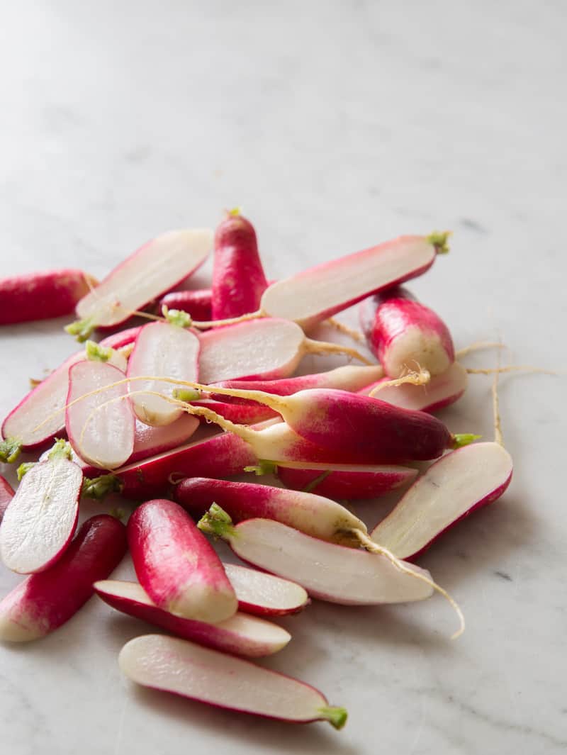 A close up of fresh radishes sliced in half from top to bottom.