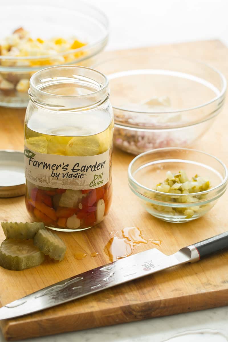Creamy Potato Salad ingredients Creamy potato salad ingredients in bowls on a wooden cutting board with a knife.