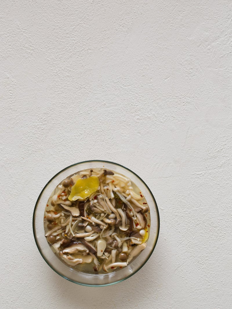Pickled Mushroom brine A clear mixing bowl of fresh mushrooms in brine.