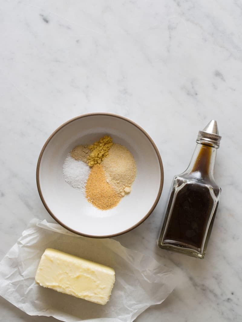 Spices for snack mix with a bottle of soy sauce and a stick of butter.