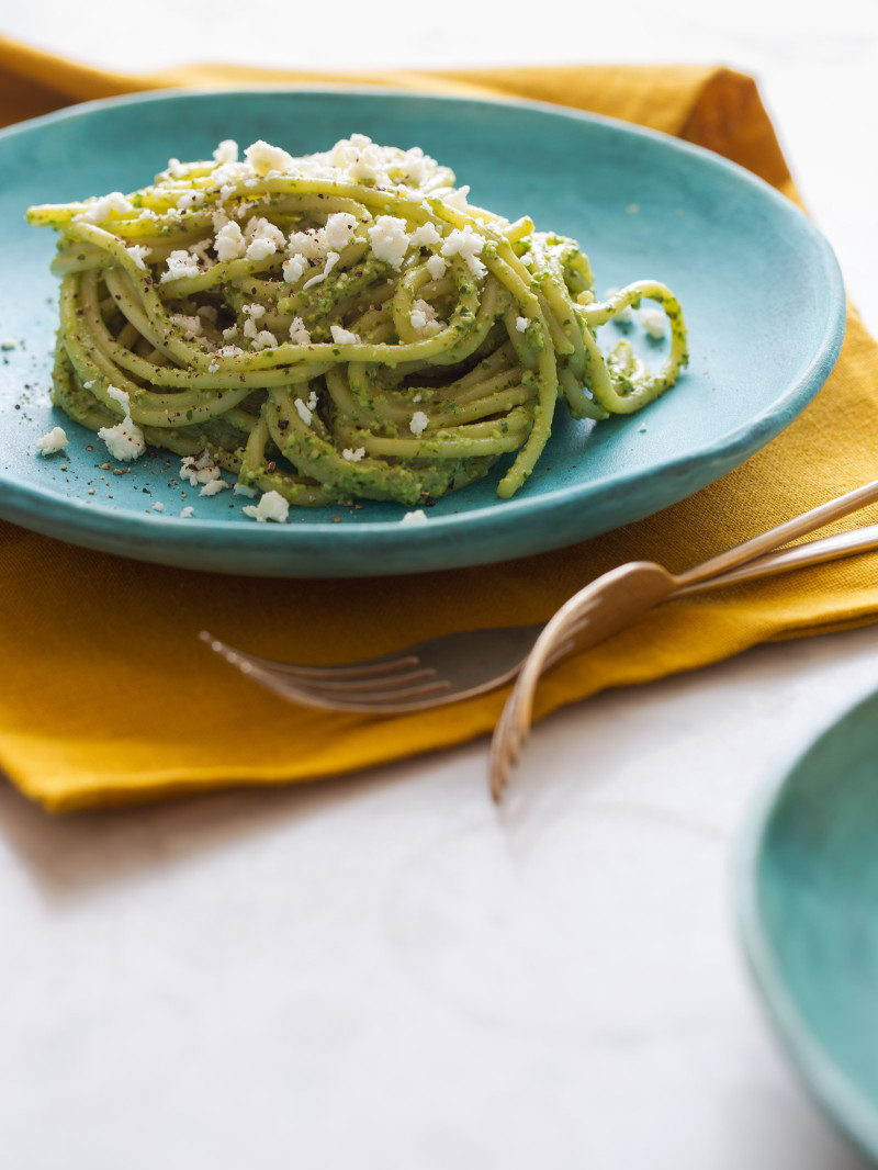 A plate of Peruvian tallarines verde on a turquoise plate with forks.