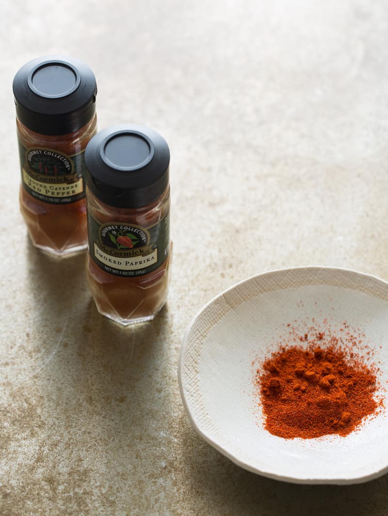 Smoked paprika in jars and poured out in a small bowl.
