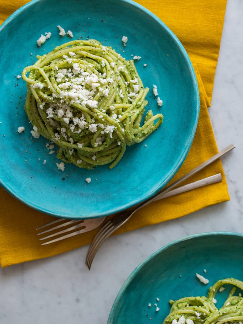 A plate of Peruvian tallarines verde on a turquoise plate with forks.