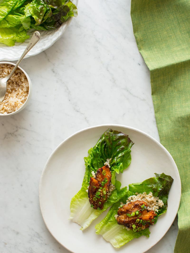 Korean style marinated spicy pork belly on brown rice and a lettuce cup.