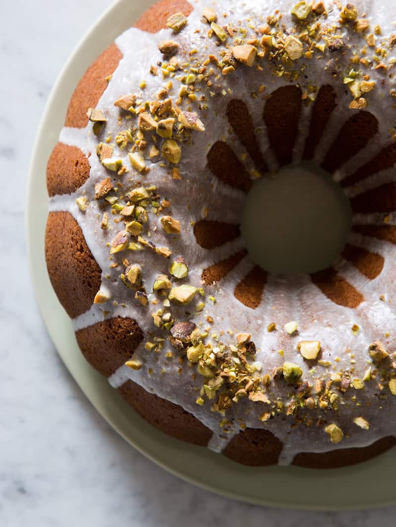 A close up of the top of a pumpkin bundt cake with pistachio glaze and pistachios.