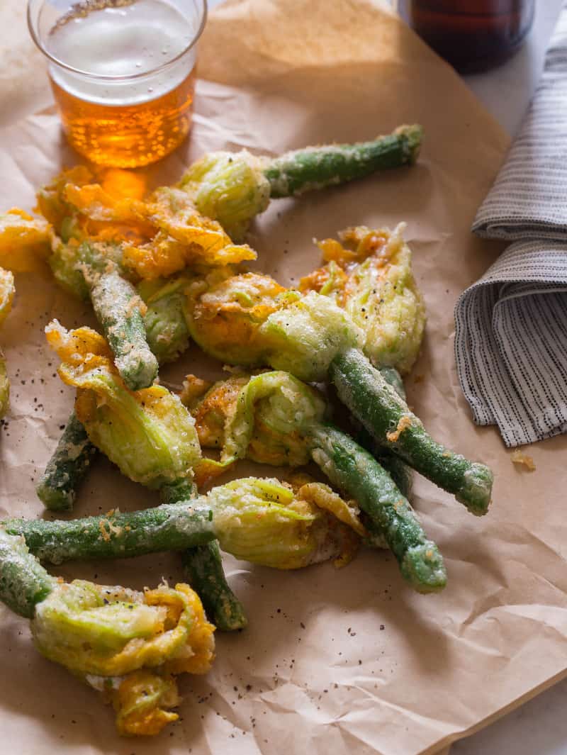 A close up of stuffed and fried squash blossoms with a drink.