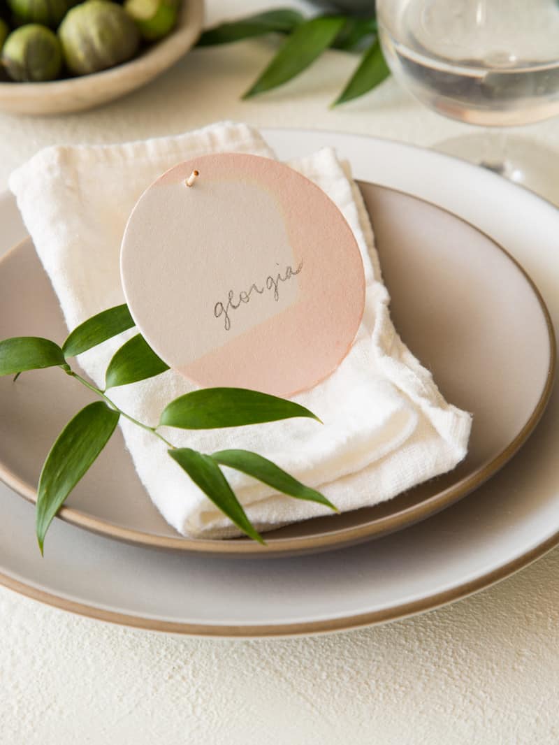 A place setting with a DIY dip dye place card and a sprig of leaves.