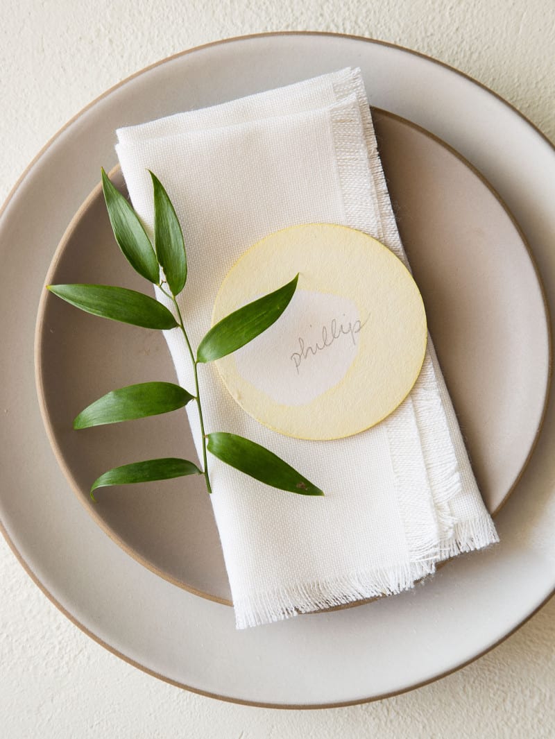 A place setting with a DIY dip dye place card and a sprig of leaves.