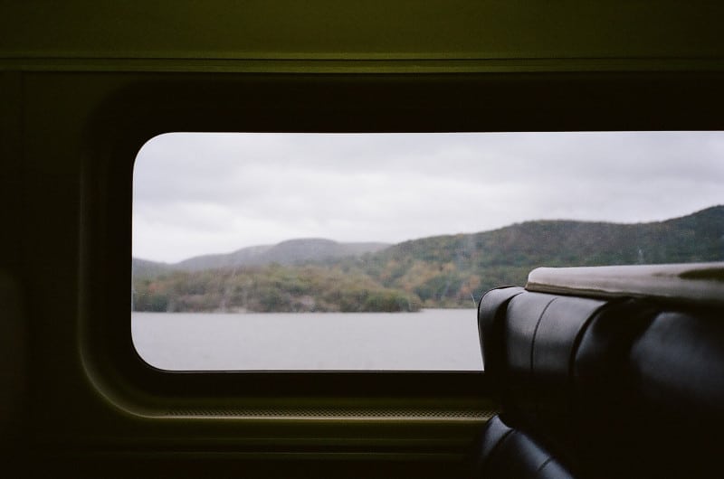 A view from a train window of water and mountains.