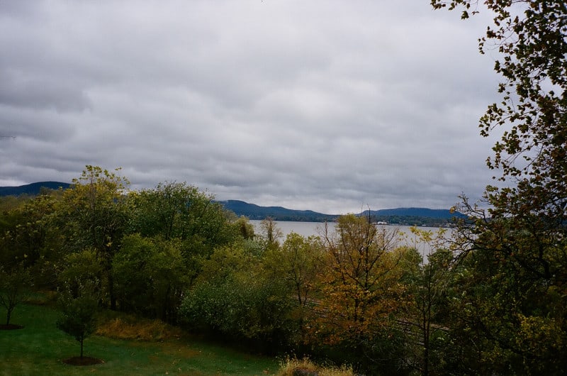 A tree lined body of water with mountains in the background.