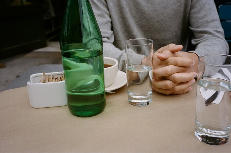 A person sitting at a table with a cup of coffee and a bottle of water.