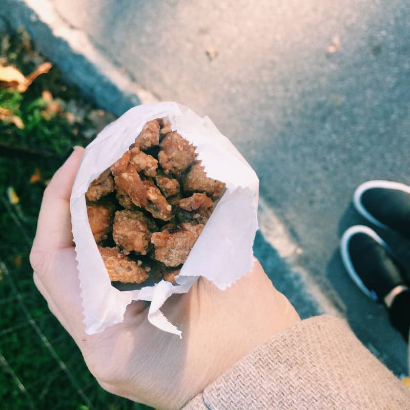 A hand holding a bag of candied cashews.