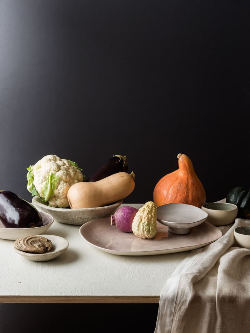 A flowerless Thanksgiving centerpiece made with fruits and vegetables on plates.