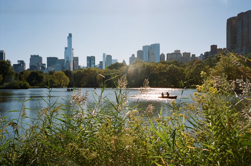 A body of water with people in boats and a city in the background. 