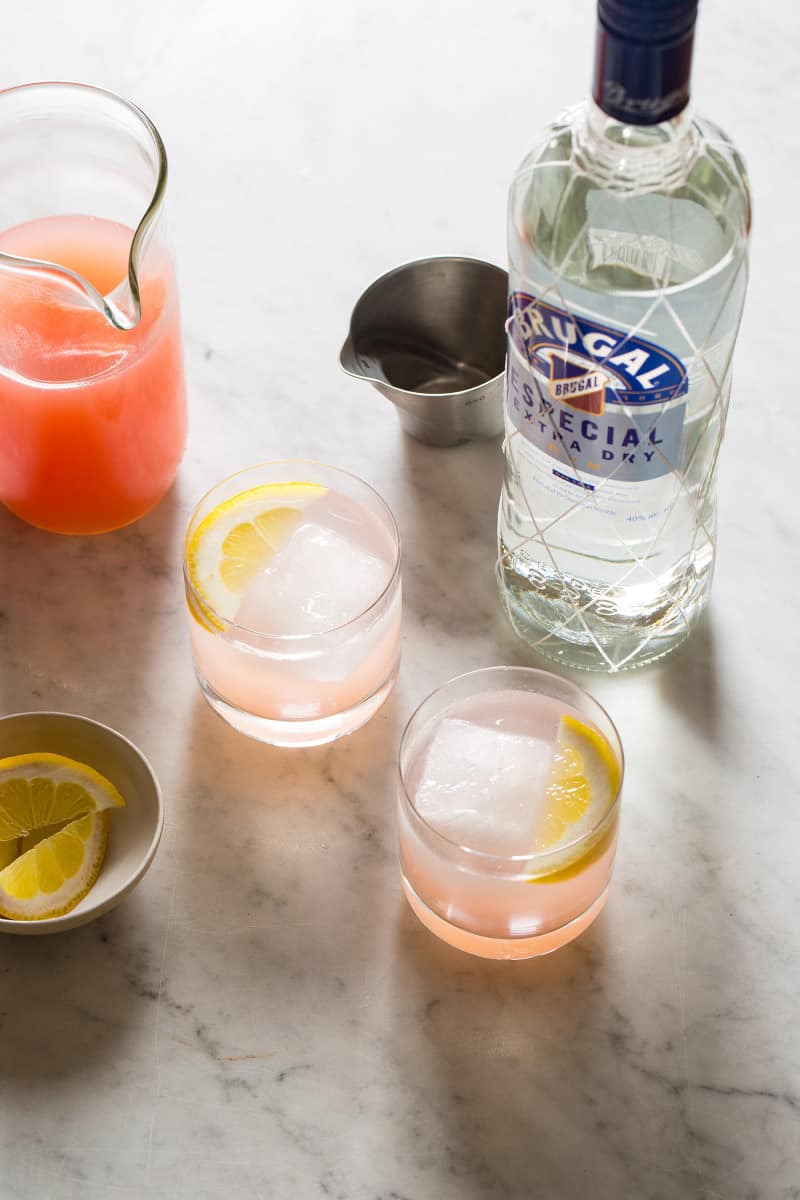 Ingredients for red grapefruit and rum spritzers garnished with lemon slices.