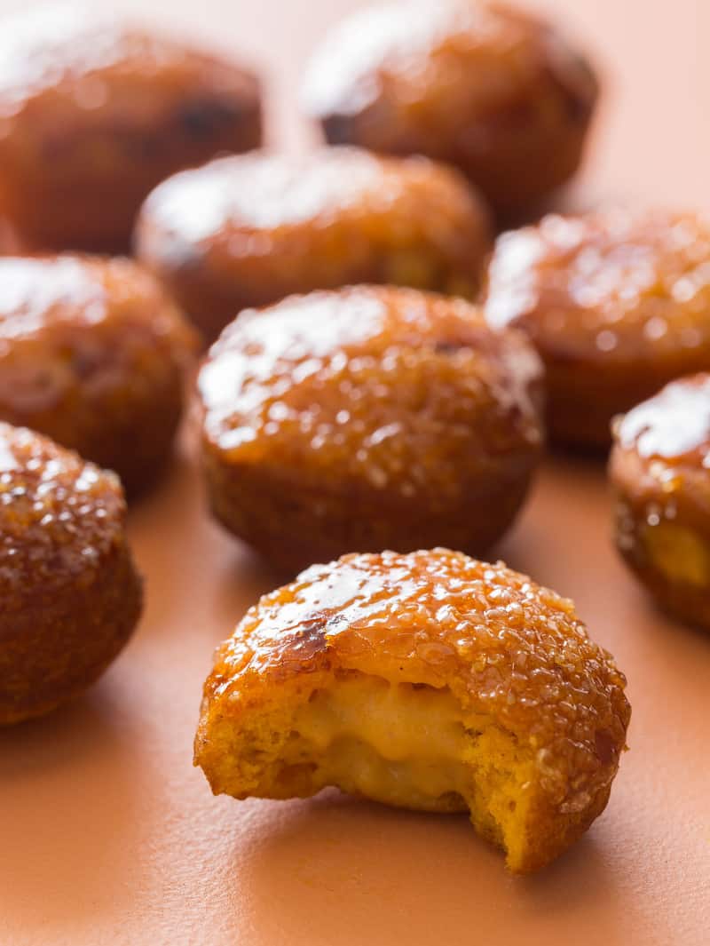 A close up of pumpkin crème brûlée doughnuts with a bite taken out of one.