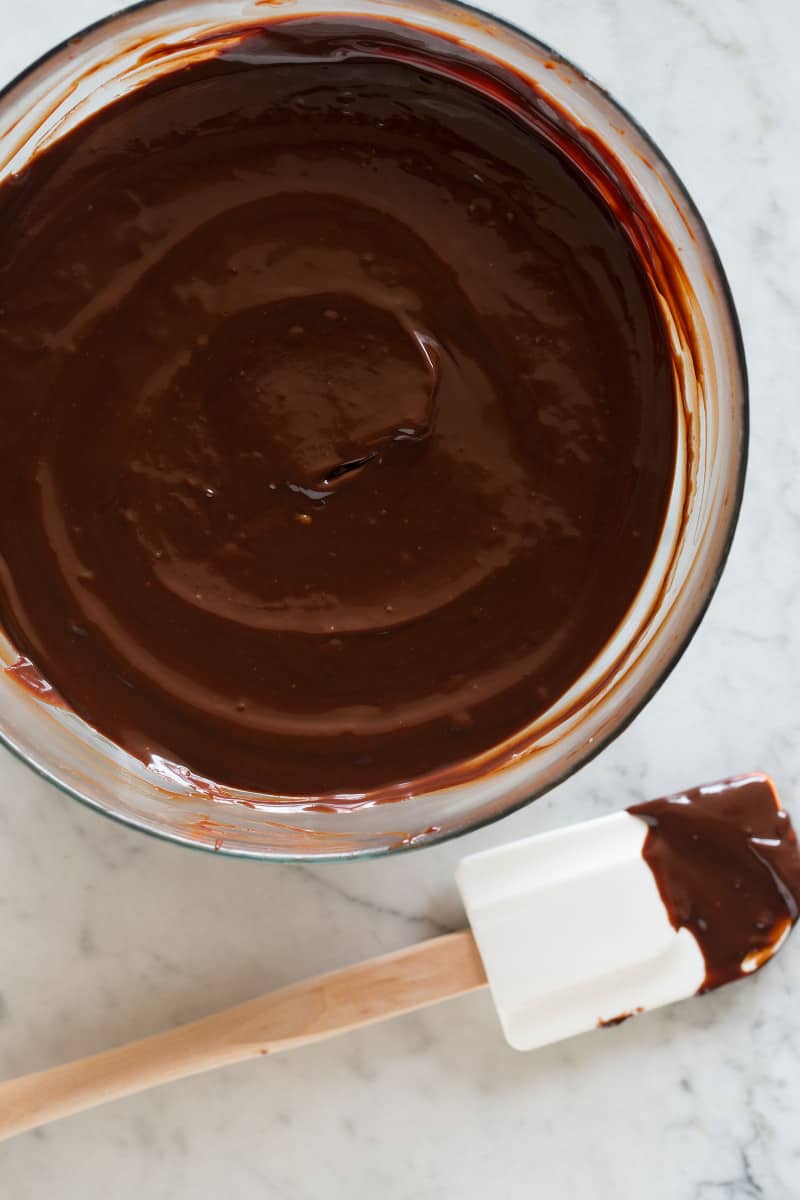 A close up of whipped Godiva ganache in a glass bowl with a spatula.