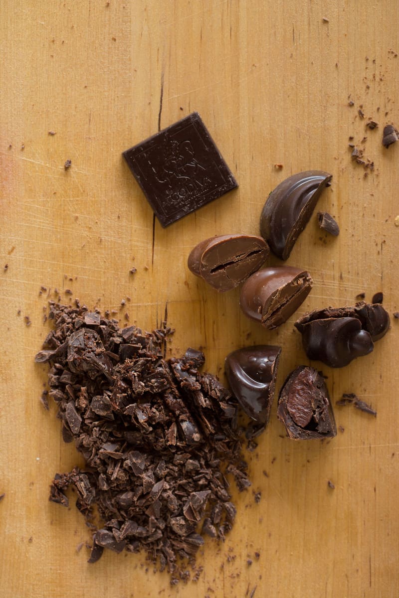 Godiva chocolates whole and chopped up on a wooden cutting board.