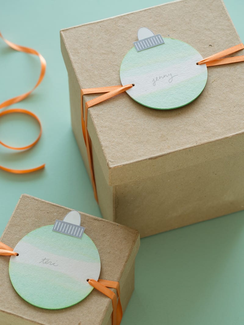 Dip dye ornament gift tags tied onto brown gift boxes.
