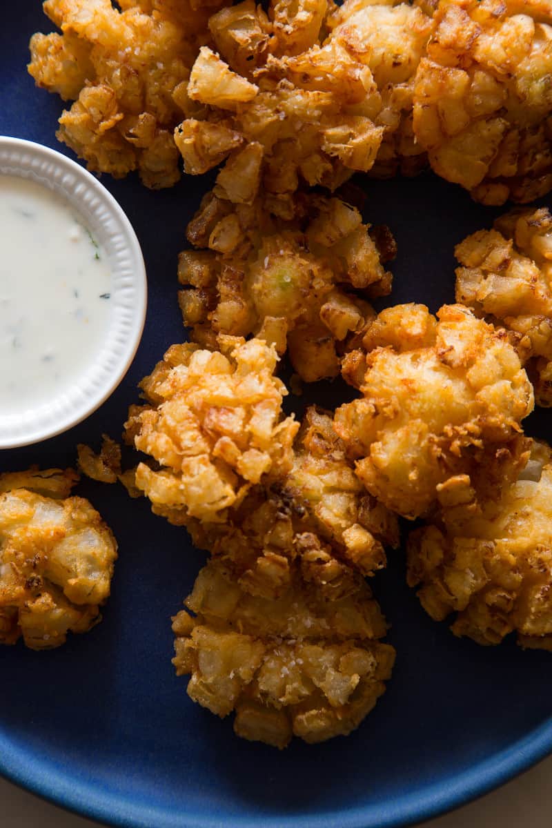 A close up of mini bloomin\' onions with a side of buttermilk ranch dipping sauce.