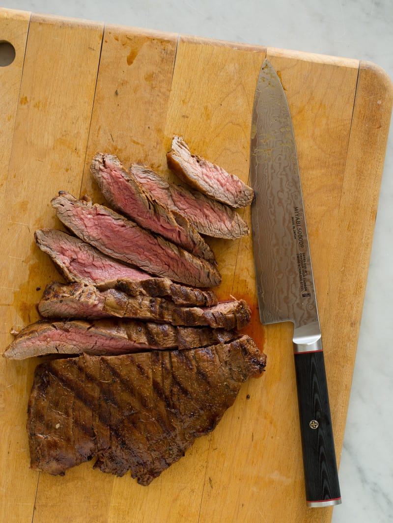 Carne Asada recipe A knife sitting on top of a wooden cutting board with carne asada.