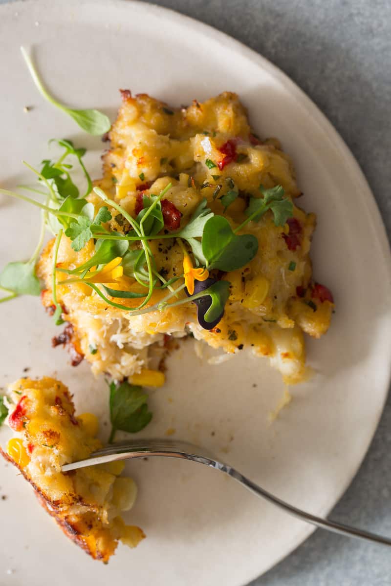 A close up of a crab cake with a bite on a fork.